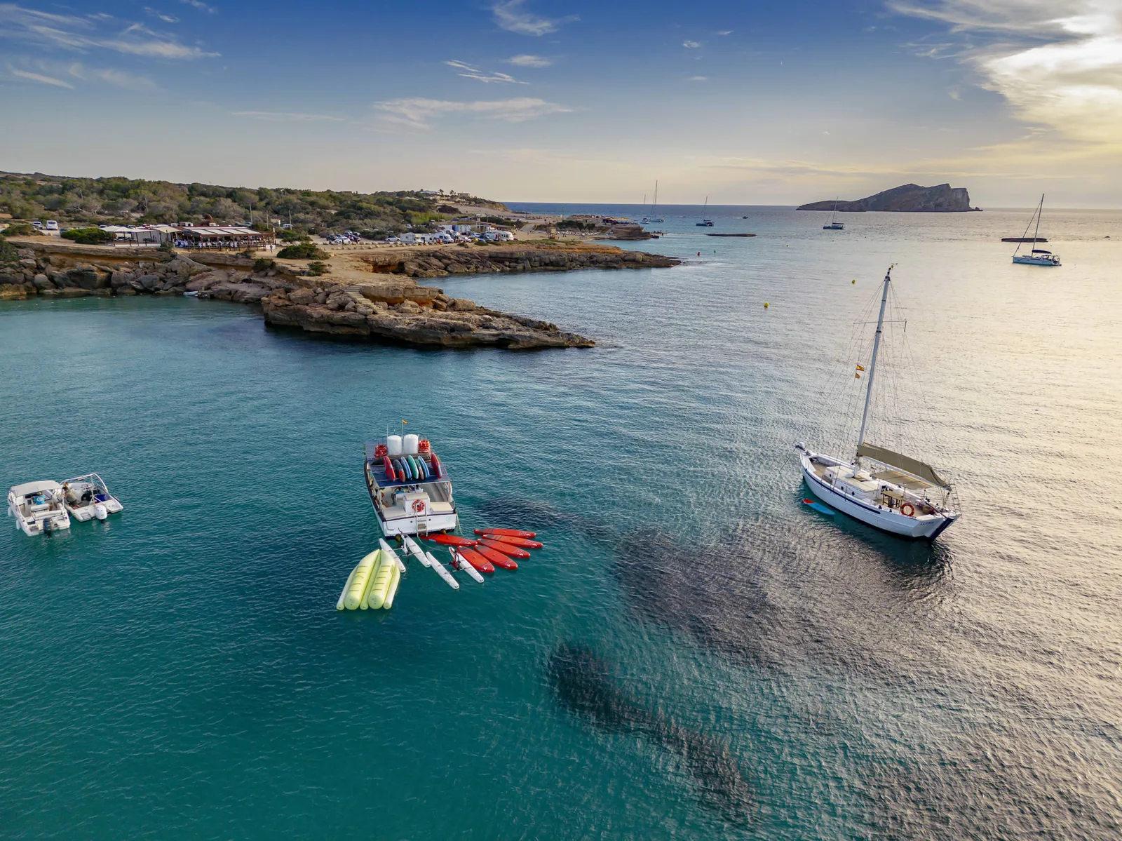 El Sinoa fondeado en una cala de Ibiza con paddles y kayaks